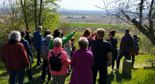 Franz Waberzeck (Mitte, mit gr&uuml;ner Jacke und Hut) erkl&auml;rt den Wandernden am Aussichtspunkt Kraftwerk Thierbach den Blick aus dem Naturfenster in Richtung Erzgebirge