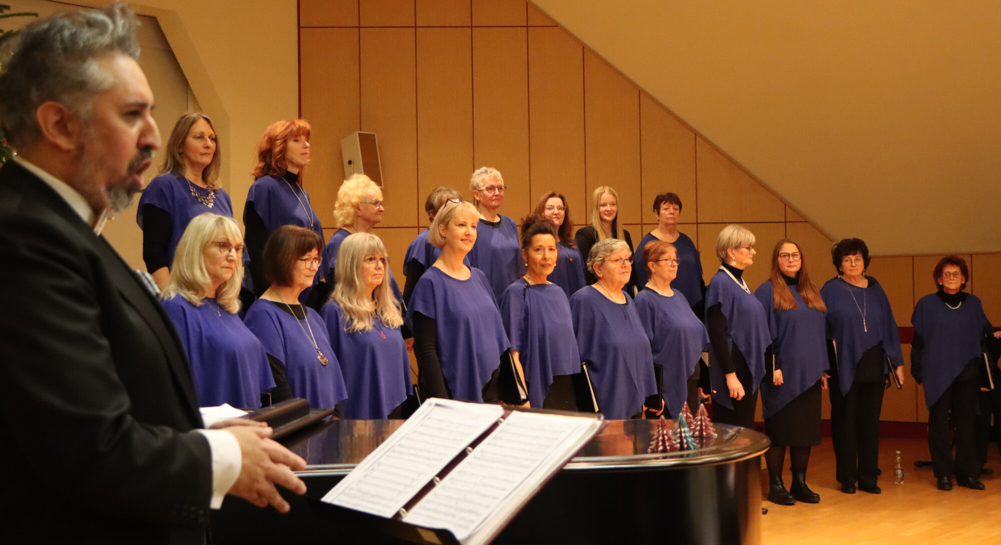 Der Frauenchor Kitzscher zum Weihnachtskonzert 2025 im Festsaal des Rathauses, im Vordergrund Chorleiter Italo Riffo bei einer Soloeinlage