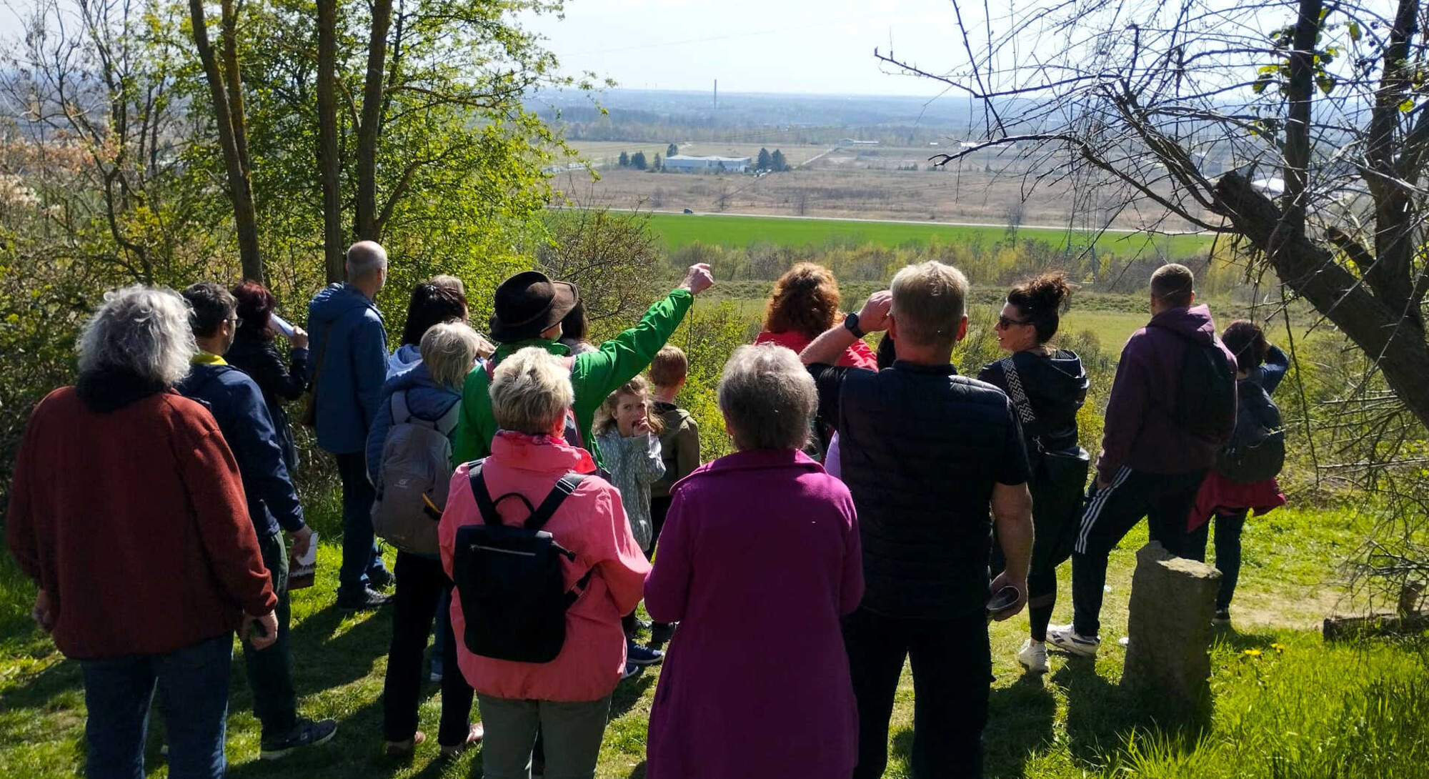 Franz Waberzeck (Mitte, mit gr&uuml;ner Jacke und Hut) erkl&auml;rt den Wandernden am Aussichtspunkt Kraftwerk Thierbach den Blick aus dem Naturfenster in Richtung Erzgebirge